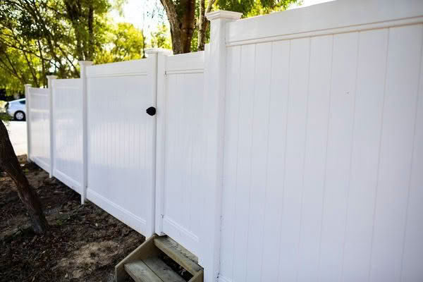 Metro PVC full privacy fence in white or grey, 1830mm high x 2400mm wide panel, durable and low-maintenance. Shown in a garden backyard setting, suitable for New Zealand conditions, can be stepped or sloped.