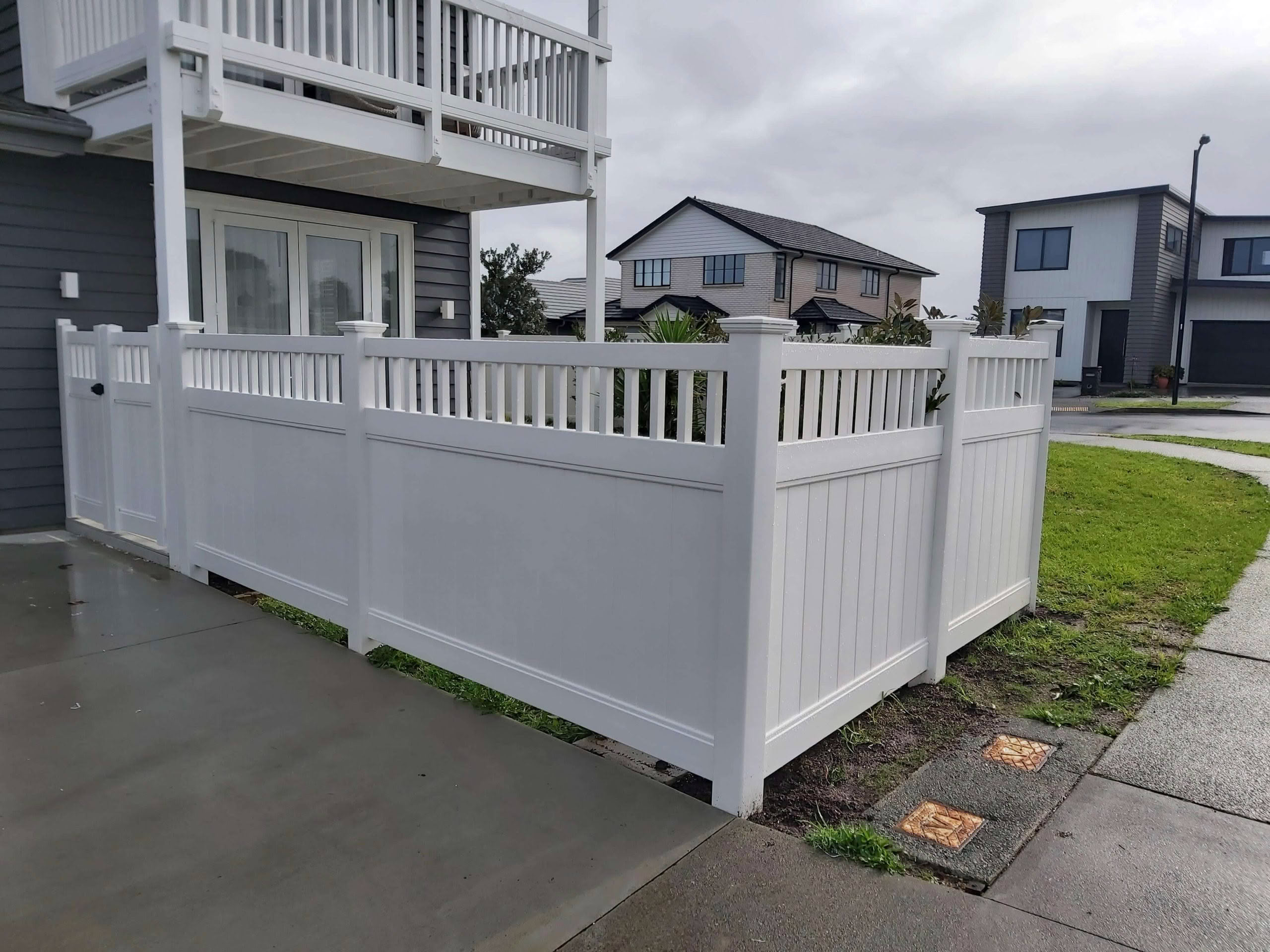Epsom PVC privacy fence with trellis top, 1830mm high x 2400mm wide panel. Shown around a modern corner house, durable and low-maintenance, available in white or with grey inserts.